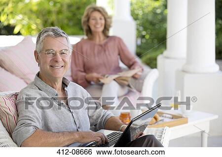 Senior man using laptop on patio View Large Photo Image Stock Photograph - Senior man using laptop on patio. Fotosearch