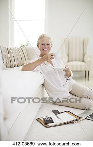 Senior woman drinking coffee on living room floor View Large Photo Image Stock Photo - Senior woman drinking coffee on living room floor. Fotosearch