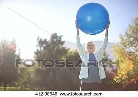 Senior woman holding fitness ball in park View Large Photo Image Stock Photograph - Senior woman holding fitness ball in park. Fotosearch