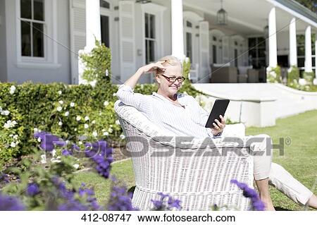 Senior woman using digital tablet in garden View Large Photo Image Stock Photo - Senior woman using digital tablet in garden. Fotosearch