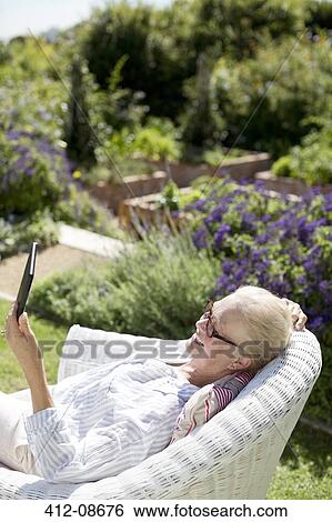 Senior woman using digital tablet in garden View Large Photo Image Stock Photograph - Senior woman using digital tablet in garden. Fotosearch