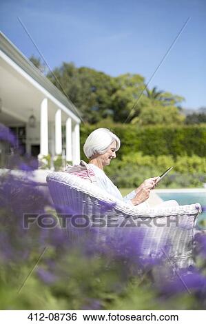 Senior woman using digital tablet in garden View Large Photo Image Stock Photograph - Senior woman using digital tablet in garden. Fotosearch