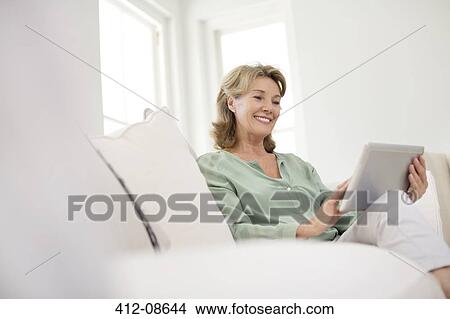 Senior woman using digital tablet on sofa View Large Photo Image Picture - Senior woman using digital tablet on sofa. Fotosearch