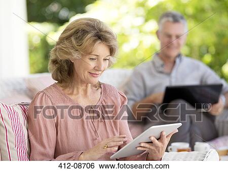 Senior woman using digital tablet on patio View Large Photo Image Stock Photograph - Senior woman using digital tablet on patio. Fotosearch