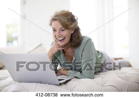 Senior woman using laptop in living room View Large Photo Image Stock Photo - Senior woman using laptop in living room. Fotosearch