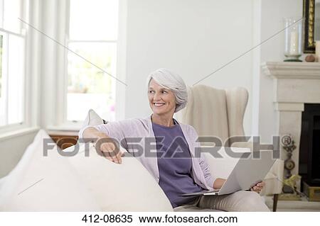 Senior woman using laptop on sofa View Large Photo Image Stock Photography - Senior woman using laptop on sofa. Fotosearch