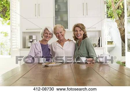 Stock Image - Senior women drinking coffee in kitchen. Fotosearch