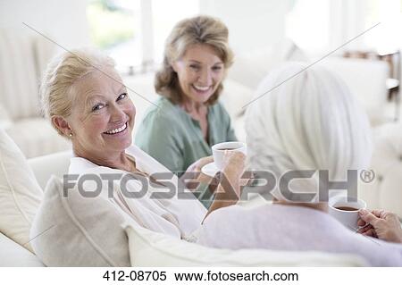 Senior women drinking coffee on sofa View Large Photo Image Stock Photography - Senior women drinking coffee on sofa. Fotosearch