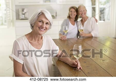 Senior women drinking white wine in kitchen View Large Photo Image Stock Photography - Senior women drinking white wine in kitchen. Fotosearch