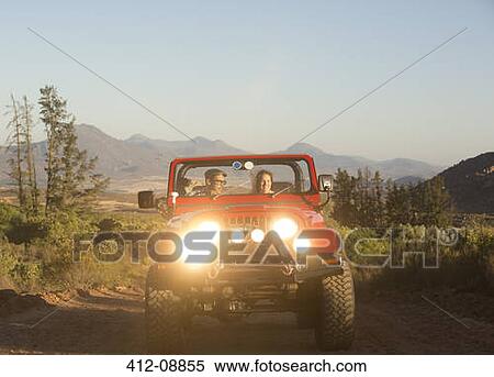 Stock Photography - Couple driving sport utility vehicle on dirt road. Fotosearch