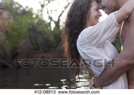 Stock Image - Couple hugging at riverside. Fotosearch