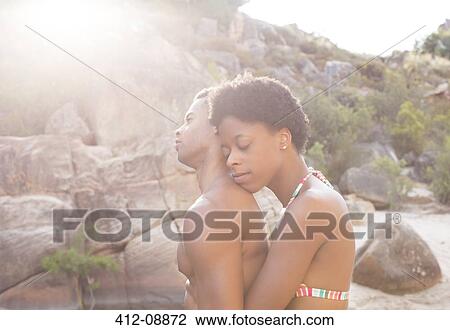 Stock Image - Couple hugging by rocks. Fotosearch
