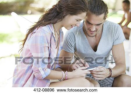 Couple listening to mp3 player outdoors View Large Photo Image Stock Photograph - Couple listening to mp3 player outdoors. Fotosearch