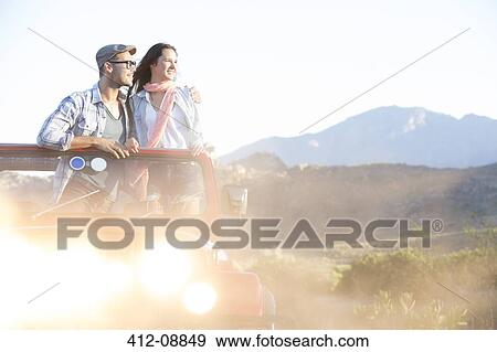 Stock Photo - Couple standing in sport utility vehicle. Fotosearch