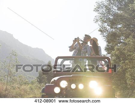Stock Image - Couple using digital camera in sport utility vehicle. Fotosearch