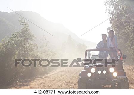 Stock Image - Friends driving sport utility vehicle on dirt road. Fotosearch