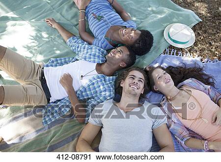 Stock Image - Friends laying on blankets outdoors. Fotosearch