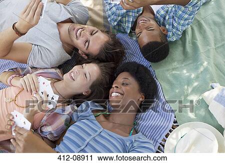 Stock Image - Friends playing cards on blankets outdoors. Fotosearch