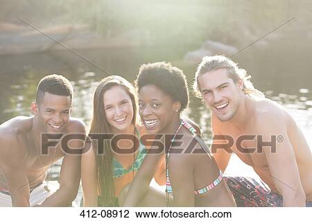 Stock Image - Friends smiling at riverside. Fotosearch