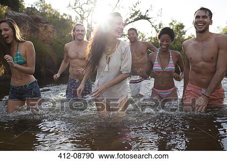 Stock Image - Friends wading in river. Fotosearch