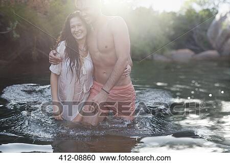 Stock Image - Friends wading in river. Fotosearch