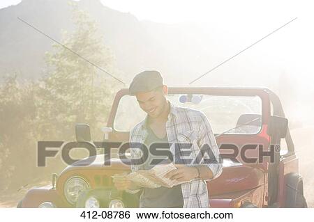 Man reading map by sport utility vehicle View Large Photo Image Stock Photograph - Man reading map by sport utility vehicle. Fotosearch