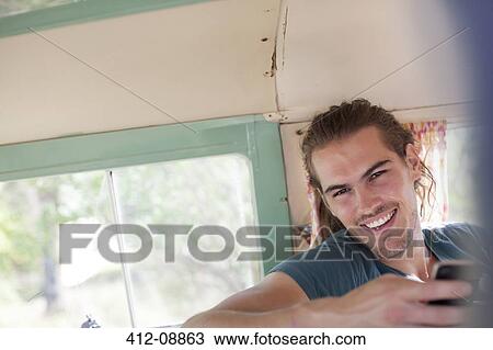 Stock Image - Man smiling in camper van. Fotosearch