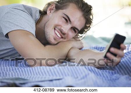 Stock Photo - Man using cell phone on picnic blanket. Fotosearch