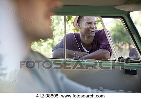 Stock Photography - Smiling man standing at camper van window. Fotosearch