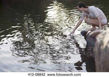 Stock Image - Woman dipping hand into lake. Fotosearch