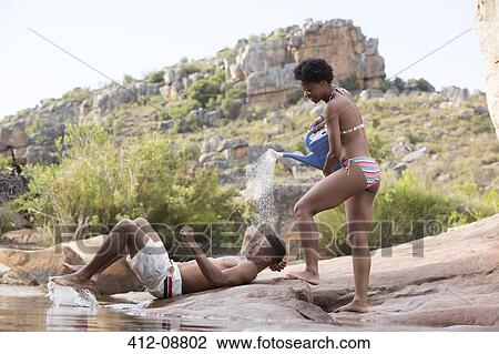 Woman splashing water on boyfriend at lakeside View Large Photo Image Stock Image - Woman splashing water on boyfriend at lakeside. Fotosearch
