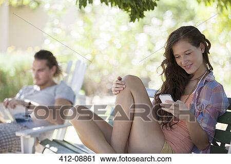 Woman using cell phone on park bench View Large Photo Image Stock Image - Woman using cell phone on park bench. Fotosearch