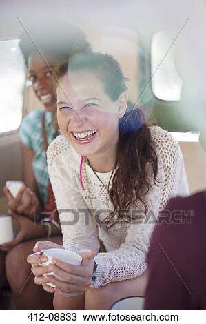Stock Image - Women drinking coffee in back seat of van. Fotosearch