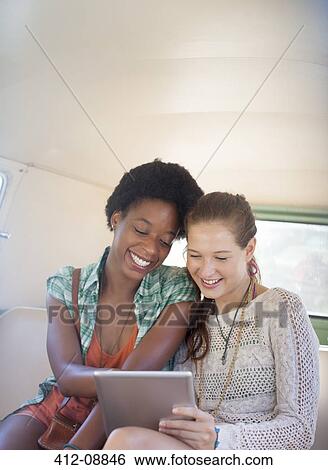 Stock Photograph - Women using digital tablet in back seat of camper van. Fotosearch