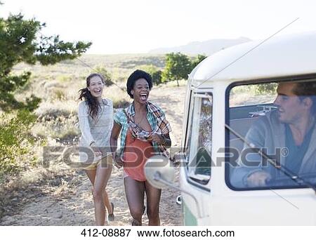 Stock Photo - Women walking to camper van on rural road. Fotosearch