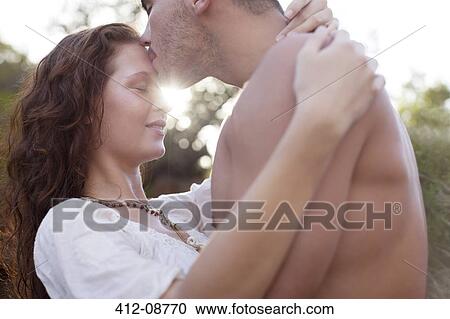 Stock Image - Young couple kissing outdoors. Fotosearch