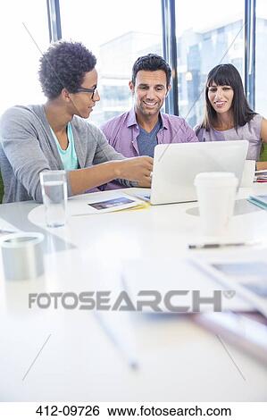 Business people sharing laptop in meeting View Large Photo Image Stock Photograph - Business people sharing laptop in meeting. Fotosearch