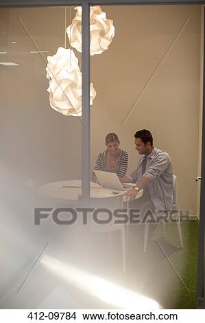 Picture - Business people using laptop at table. Fotosearch