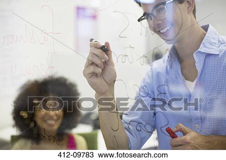 Stock Image - Business people writing on glass in office. Fotosearch
