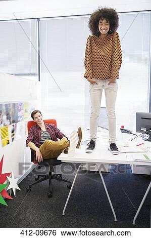 Business woman standing on table in office View Large Photo Image Stock Photograph - Business woman standing on table in office. Fotosearch