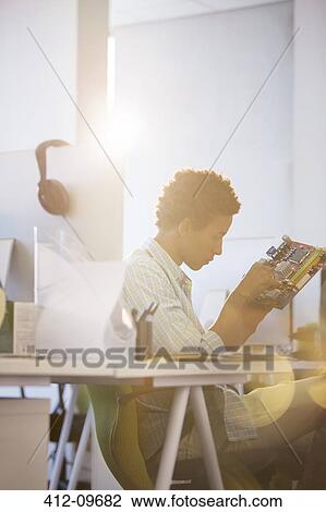 Businessman examining circuit board in office View Large Photo Image Stock Image - Businessman examining circuit board in office. Fotosearch