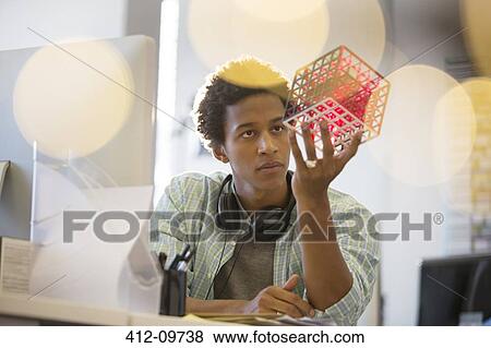 Businessman examining cube at desk in office View Large Photo Image Stock Photo - Businessman examining cube at desk in office. Fotosearch