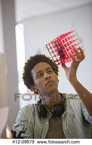 Businessman examining cube in office View Large Photo Image Stock Photo - Businessman examining cube in office. Fotosearch