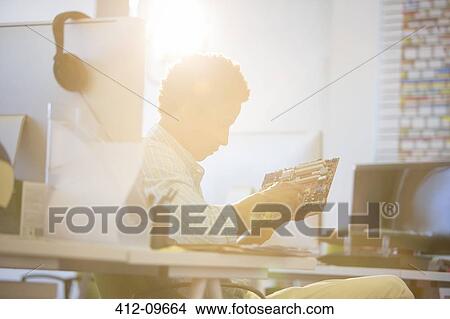 Businessman holding circuit board in sunny office View Large Photo Image Picture - Businessman holding circuit board in sunny office. Fotosearch