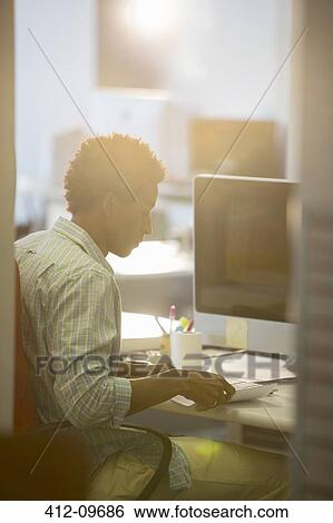 Stock Photograph - Businessman reading at desk in office. Fotosearch