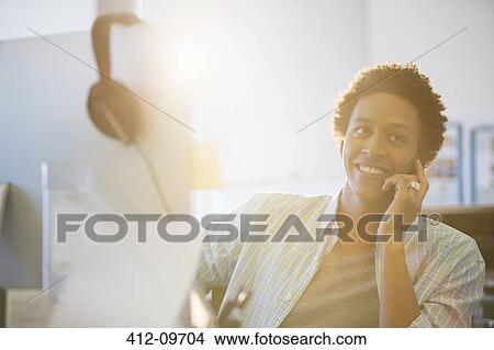 Picture - Businessman talking on cell phone in office. Fotosearch