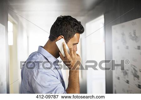 Businessman talking on cell phone in corridor View Large Photo Image Stock Photo - Businessman talking on cell phone in corridor. Fotosearch