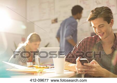 Businessman using cell phone in office View Large Photo Image Stock Photo - Businessman using cell phone in office. Fotosearch