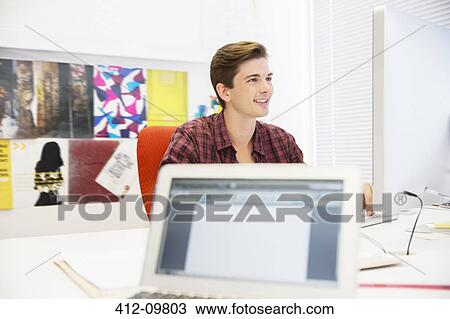 Stock Image - Businessman working at desk in office. Fotosearch