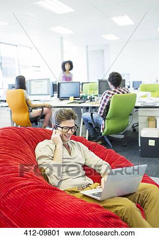 Businessman working in beanbag chair in office View Large Photo Image Stock Image - Businessman working in beanbag chair in office. Fotosearch